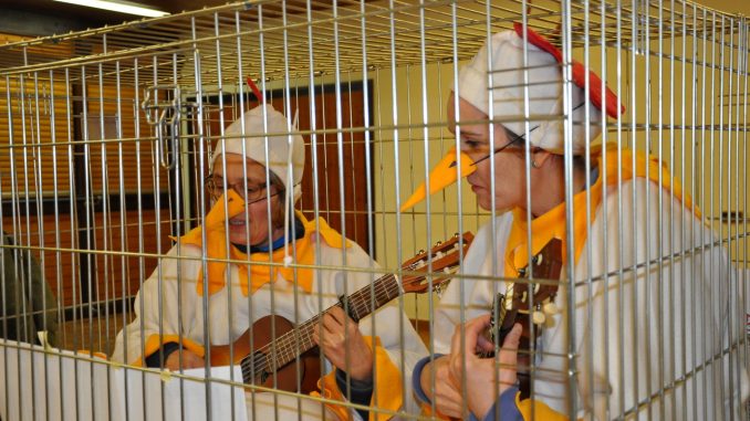 Frauen stellen gefangene Hühner dar und singen